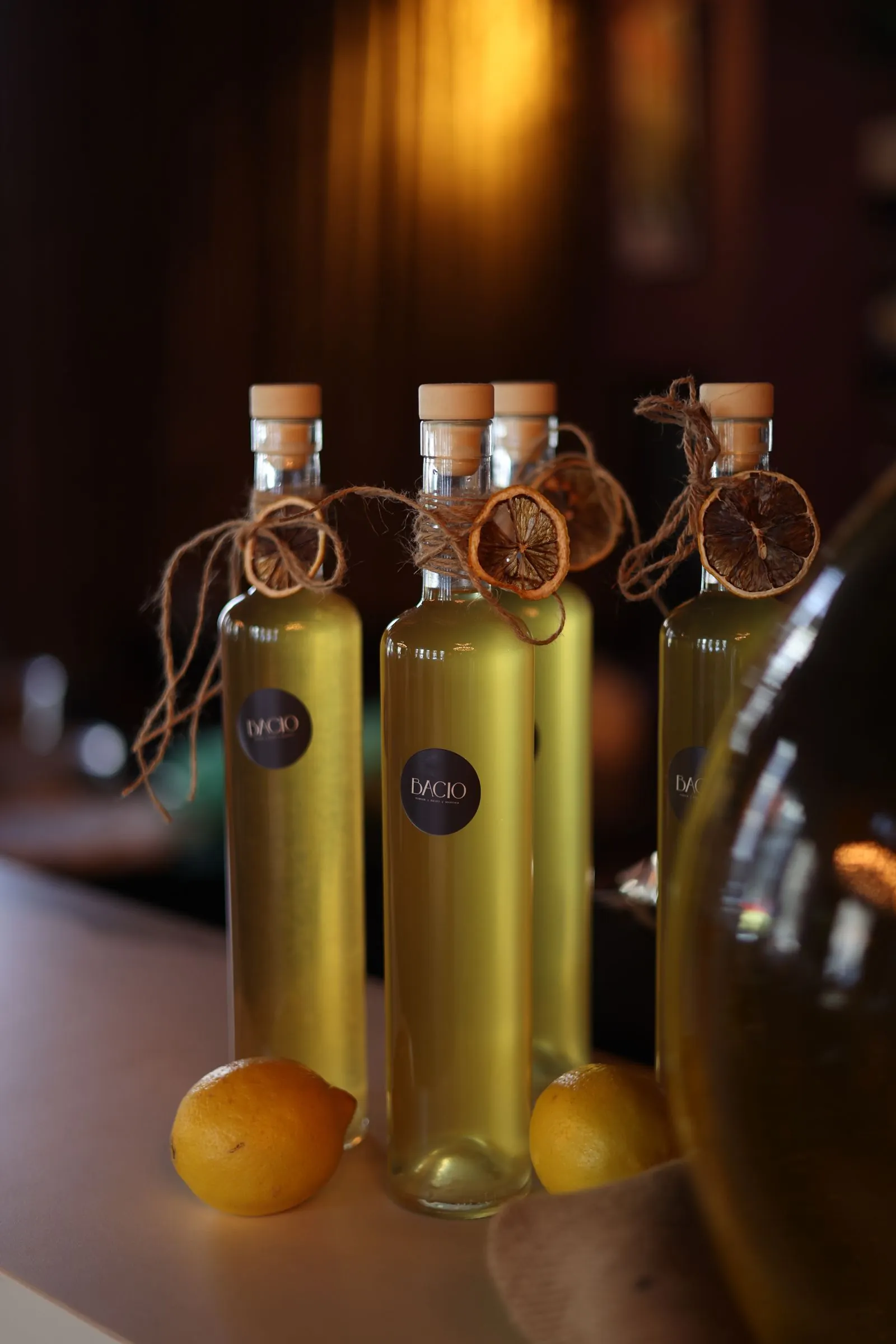 Illustrative photograph: Glass olive oil bottles and fresh lemons on a wooden counter.