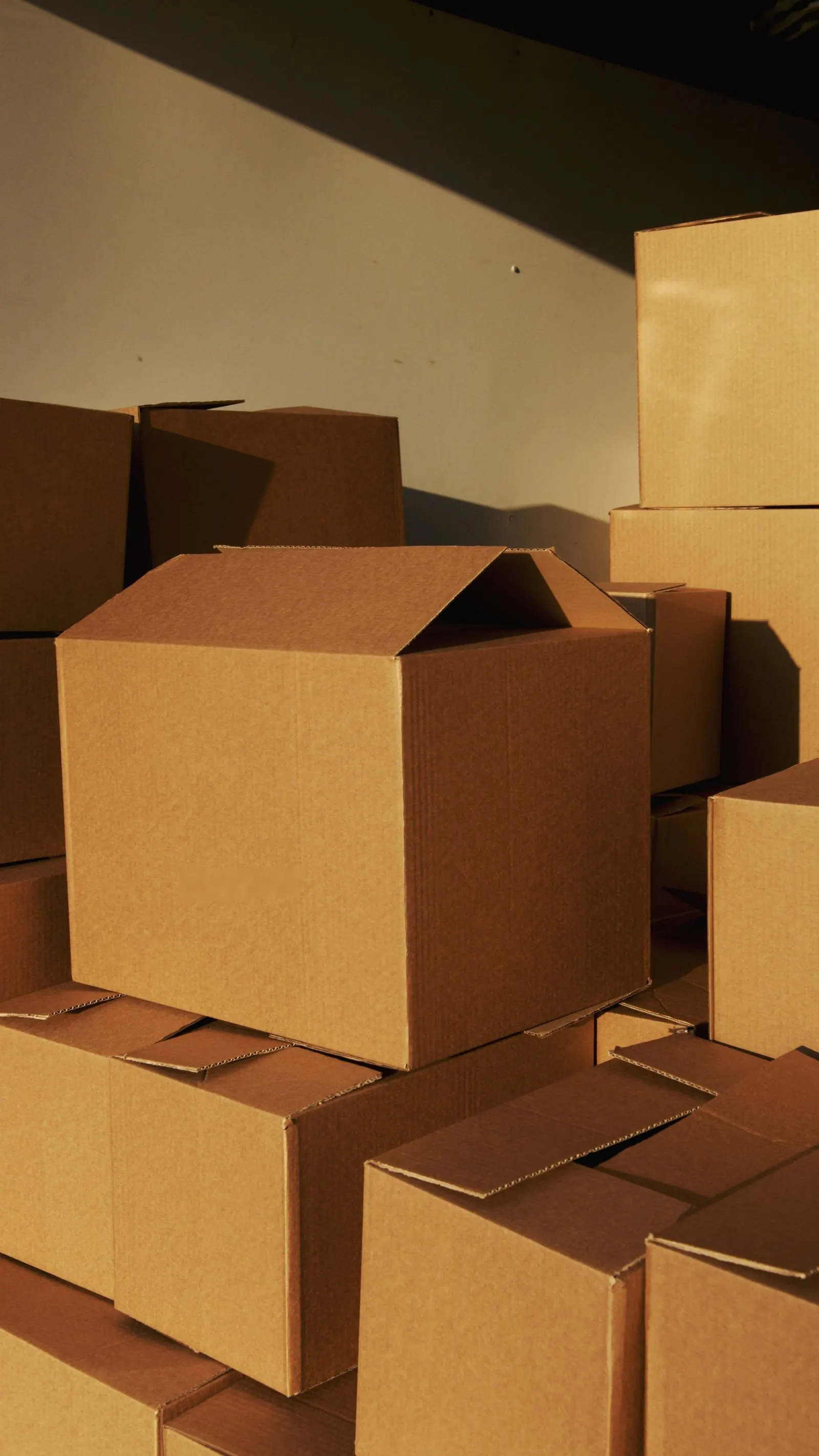 Illustrative photograph: Plain cardboard shipping boxes stacked together.