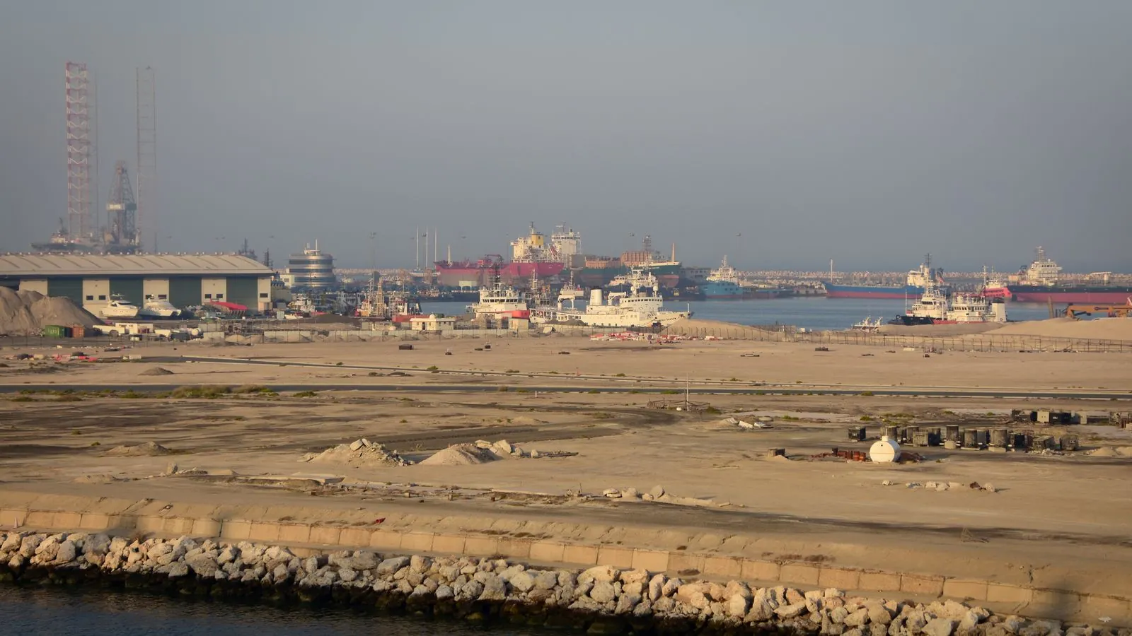 Navires et bâtiments portuaires au bord de l’eau sous un ciel brumeux