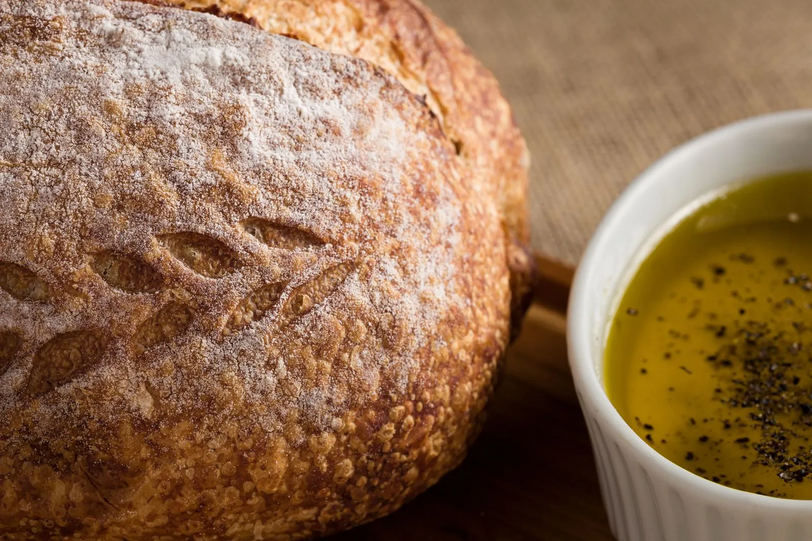 Illustrative photograph: A rustic loaf of bread beside a bowl of golden olive oil seasoned with pepper.